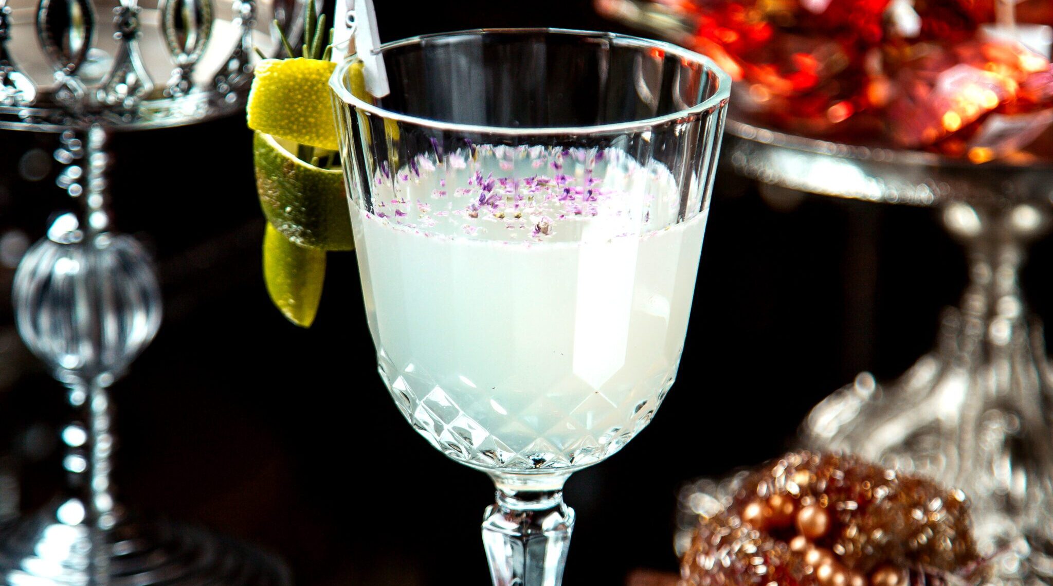 a crystal glass with white cocktail garnished with lemon zest